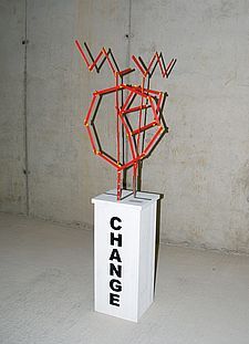 Foto der Skulptur „CHANGE“ aus roten beweglichen Maßstäben auf einer Säule